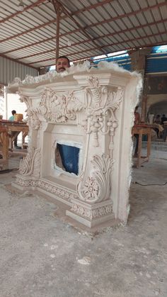 a man standing next to a white fireplace in a room