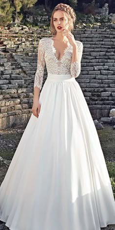 a woman in a white wedding dress posing for the camera with her hand on her face