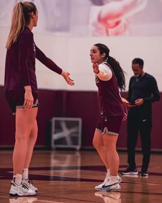 two girls are playing basketball on the court while one girl is holding her hand out