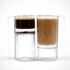 two glasses filled with liquid sitting next to each other