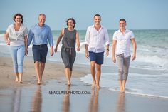 four people are walking along the beach together