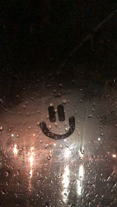 a rain covered window with a smiley face drawn on it