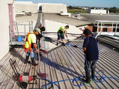 four men are cleaning the roof of a building