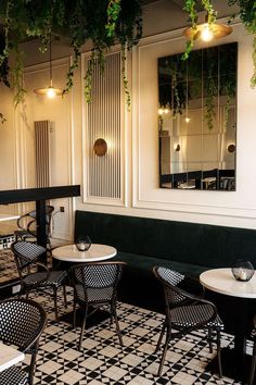 tables and chairs are lined up against the wall with plants growing over them in front of mirrors