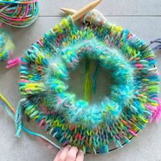 someone is making a colorful yarn wreath