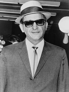 an older man in a suit and tie wearing sunglasses, a hat and a fedora