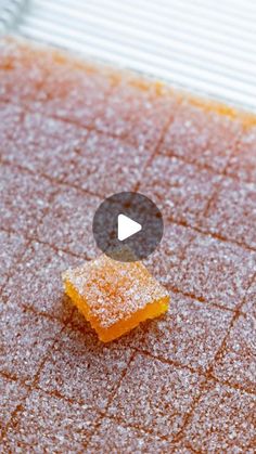 a piece of orange cake sitting on top of a table covered in powdered sugar