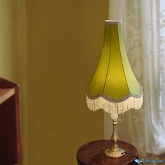 a lamp that is sitting on top of a wooden table next to a window with curtains