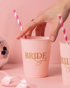 the bride squad cups are pink with gold lettering and two straws in each cup