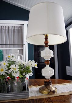 a lamp sitting on top of a table next to vases with flowers in them