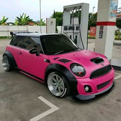 a pink and black car parked at a gas station