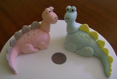 two toy dinosaurs sitting on top of a white disc