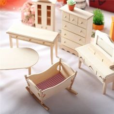 there are many miniature wooden furniture on the table and in the room, including a doll's house