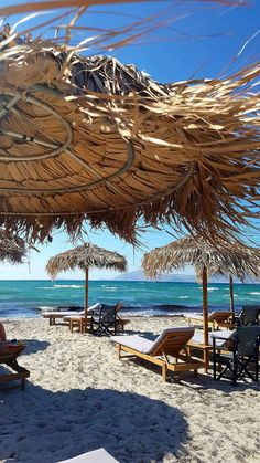 people are sitting under straw umbrellas on the beach