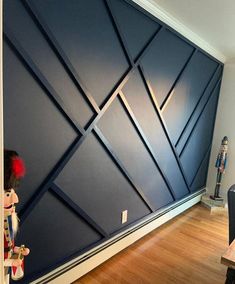 an empty room with wooden flooring and blue wall covering the entire area, along with a black chair