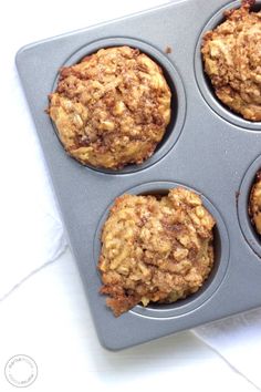 four muffins in a cupcake pan on a white counter top, ready to be eaten