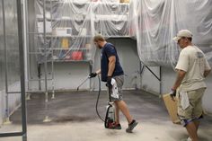 two men are cleaning the floor with vacuums