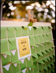 a note pinned to a green wall with white origami pieces on it that say sup us a note