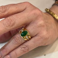 This one of a kind Vintage Inspired Jade & Diamond Ring is crafted in 18k Yellow Gold. A chunky statement ring with Mid-Century style! The jade features a deep forest green hue with rich saturation. The oval shaped cabochon cut jade is set in a bezel. A collection of accent diamonds sparkle at the center of the bold ring. Modern and expertly designed. The ring measures just under 13mm wide. Finished on a tapered and thick 18 karat yellow gold band. A stunning gift for you or your loved one. The Luxury Green Emerald Open Ring, Mens Gold Ring Vintage, Jade Wedding Ring, Panna Ring, Jade Diamond Ring, Jade Jewelry Design, Melted Gold, Jade Engagement Ring, Bezel Diamond Rings