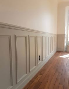 an empty room with wood floors and white walls, painted in light gray paint on the wall