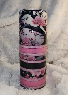 a pink and black vase sitting on top of a white blanket