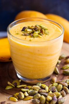 a glass filled with yellow liquid surrounded by nuts