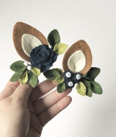 two handmade flower brooches with green leaves and blue flowers in the middle