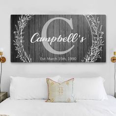 a bed with white pillows and a wooden sign above it that says campbell's