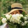 a man wearing a straw hat holding a bouquet of white flowers