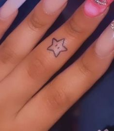 a small star tattoo on the middle finger