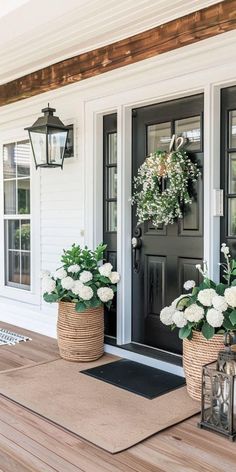 two planters with white flowers are on the front porch