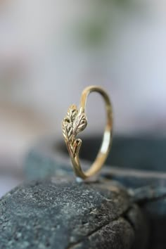 a gold ring with leaves on it sitting on top of a stone slab in front of a blurry background