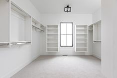 an empty room with white walls and open shelvings on either side of the window