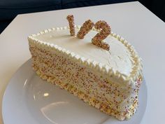 a cake with white frosting and sprinkles on it sitting on a plate