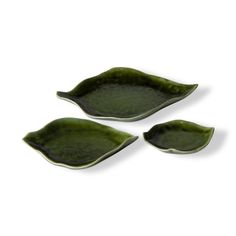 three green leaf shaped dishes sitting on top of each other