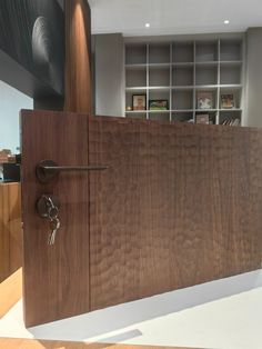 an open wooden door with two keys in the middle and bookshelves behind it