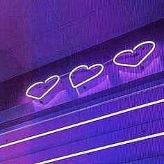 a neon sign that is on the side of a building with hearts painted on it