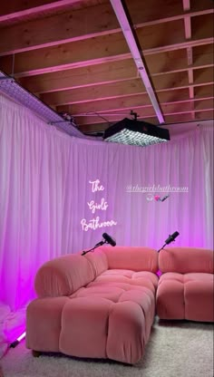 a pink couch sitting in front of a purple curtain