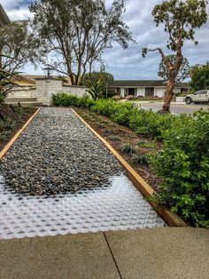 a walkway made out of rocks and gravel with trees in the background