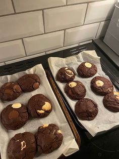 two trays filled with cookies sitting on top of a stove next to each other