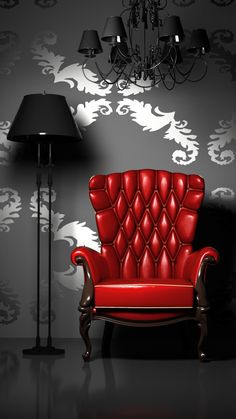 a red chair sitting in front of a lamp on a black floor next to a wall