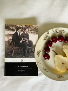 a plate with some fruit on it next to a book and an image of two people