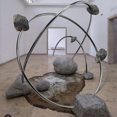 a sculpture is shown in an empty room with rocks on the floor and a skylight above it