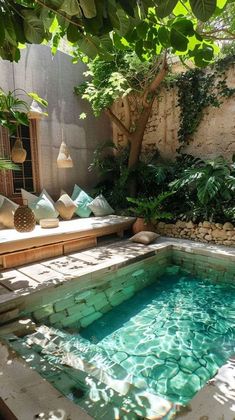 an outdoor swimming pool surrounded by greenery and stone walls, with seating area in the background