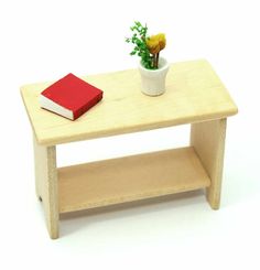 a small wooden table with a red book on it and a flower in a pot