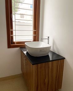 a white bowl sitting on top of a wooden counter in front of a large window