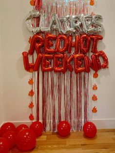 red balloons and streamers are hanging from the wall in front of a party sign