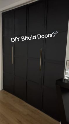 a room that has some black doors and wood flooring on the walls, with white lettering reading diy bifold doors