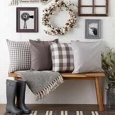 a wooden bench with pillows and pictures on the wall above it, along with a wreath