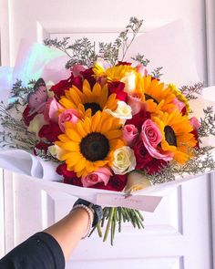 a bouquet of sunflowers and roses is being held by someone